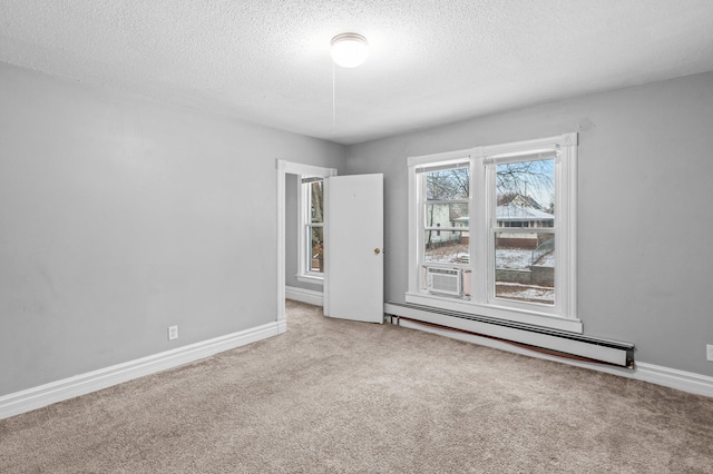 carpeted empty room featuring a baseboard radiator and a textured ceiling