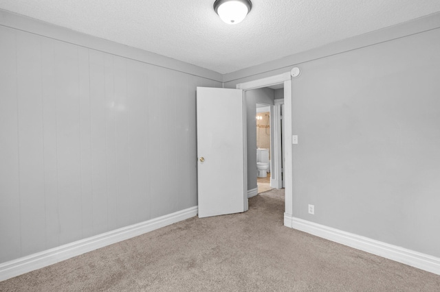 empty room with light carpet and a textured ceiling