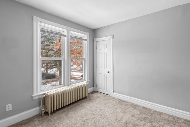 spare room featuring light colored carpet and radiator heating unit