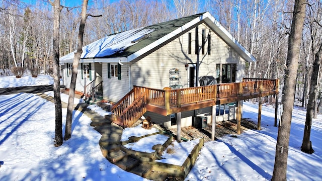 snow covered house with central AC unit and a wooden deck