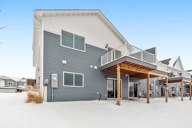 snow covered back of property featuring a wooden deck