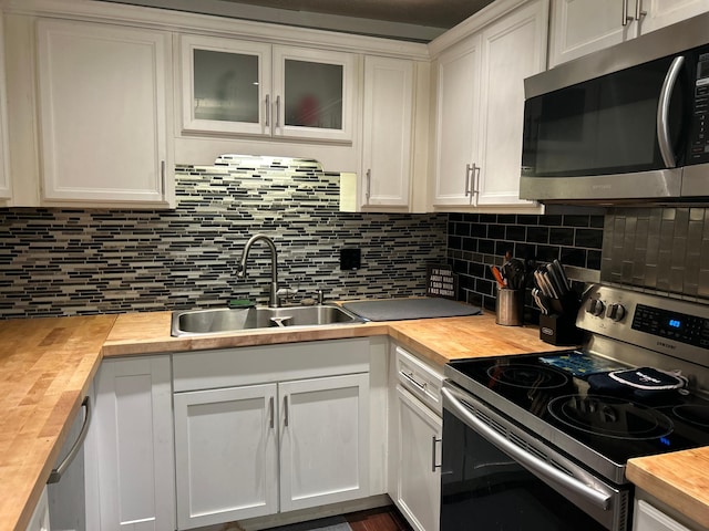 kitchen featuring wood counters, tasteful backsplash, sink, white cabinets, and stainless steel appliances