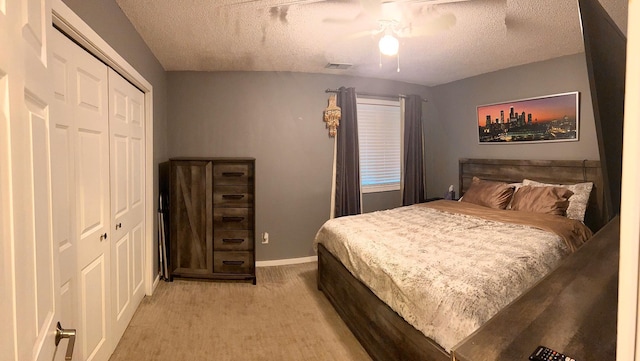 carpeted bedroom with a textured ceiling, ceiling fan, and a closet