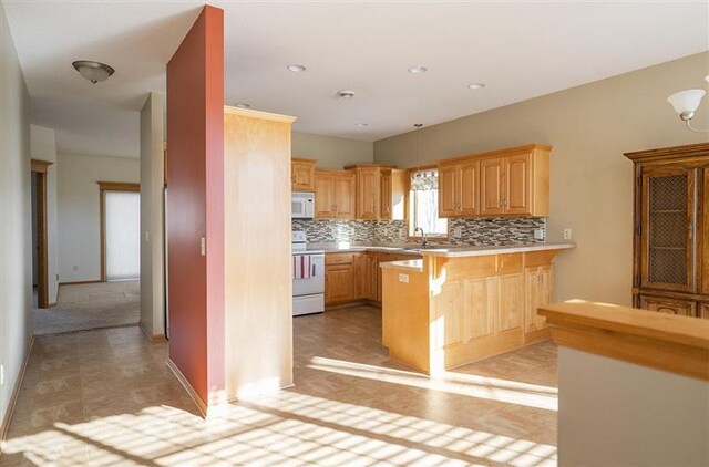 kitchen featuring a breakfast bar, sink, kitchen peninsula, white appliances, and backsplash