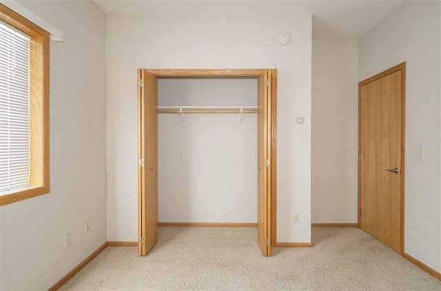 unfurnished bedroom with light carpet and a closet