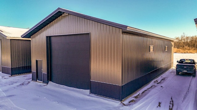 snow covered structure featuring a garage