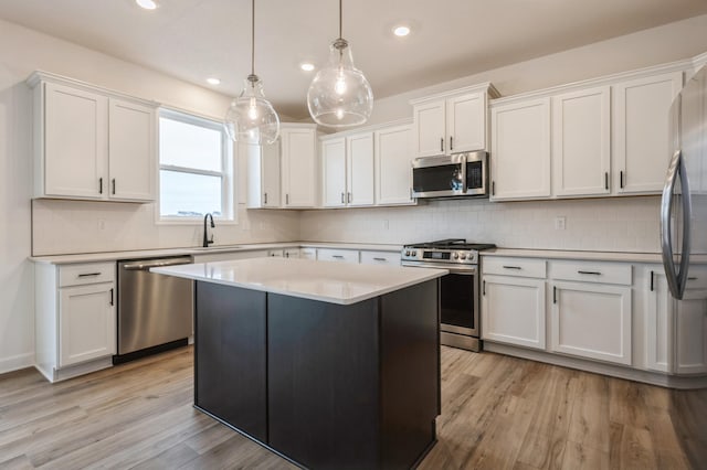 kitchen with white cabinetry, appliances with stainless steel finishes, decorative light fixtures, and a kitchen island