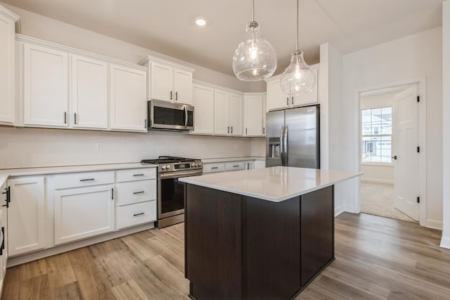 kitchen with a kitchen island, pendant lighting, tasteful backsplash, white cabinets, and stainless steel appliances