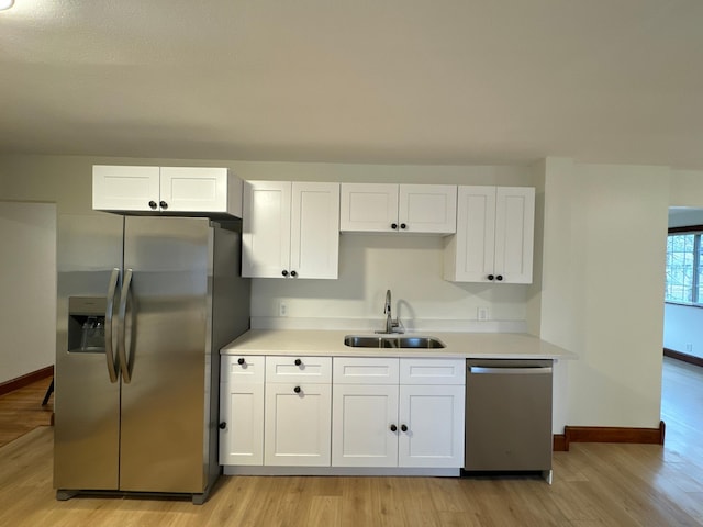 kitchen featuring white cabinetry, stainless steel appliances, sink, and light wood-type flooring