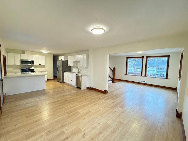 kitchen with appliances with stainless steel finishes, sink, white cabinets, and light hardwood / wood-style floors