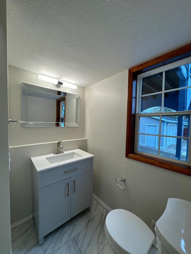 bathroom featuring vanity, a textured ceiling, and toilet