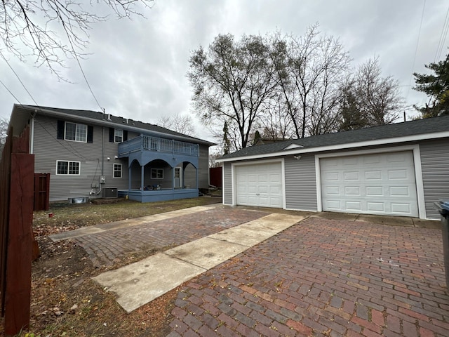 view of front facade with cooling unit, a garage, an outdoor structure, and a balcony