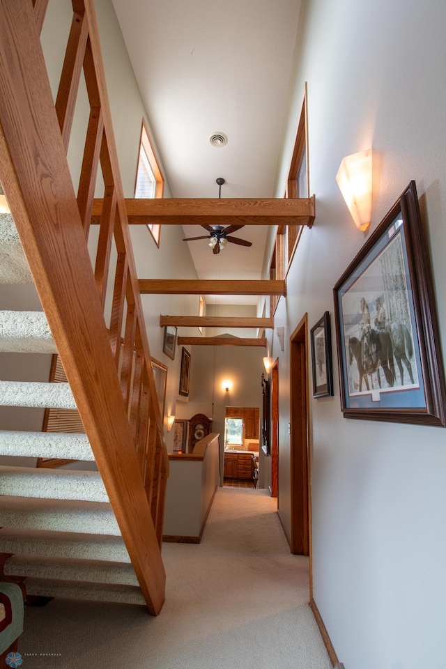 corridor featuring light carpet and a high ceiling