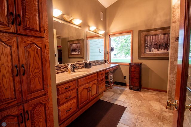 bathroom featuring vanity, lofted ceiling, and backsplash