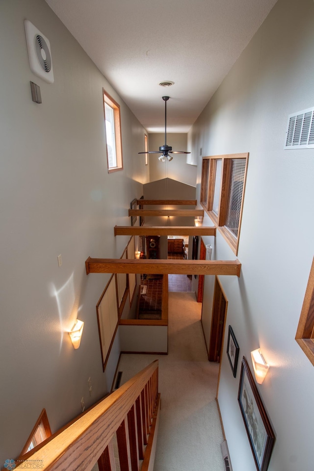 hallway featuring a high ceiling and light colored carpet