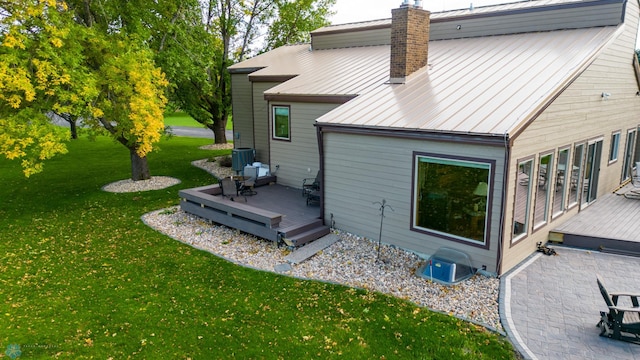 rear view of property featuring central AC, a lawn, and a deck