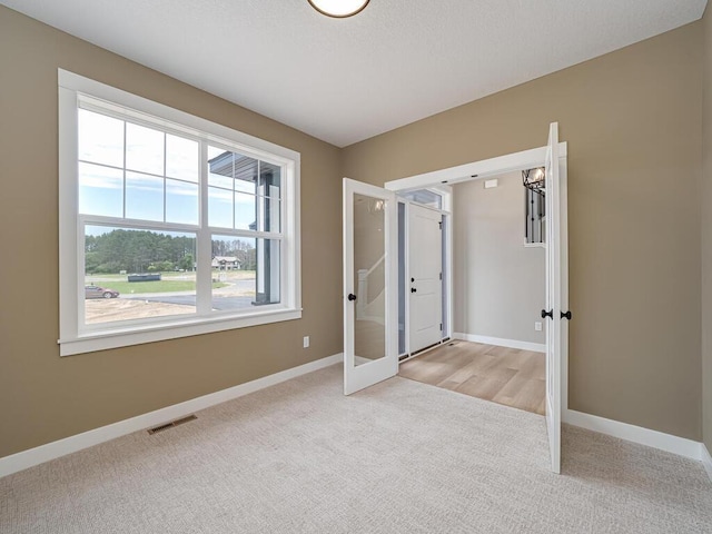 unfurnished bedroom with light carpet and french doors