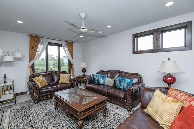 living room featuring ceiling fan and a textured ceiling