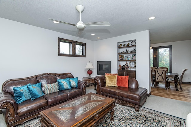 carpeted living room featuring ceiling fan and a textured ceiling