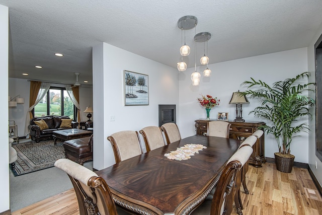 dining space featuring light hardwood / wood-style flooring and a textured ceiling