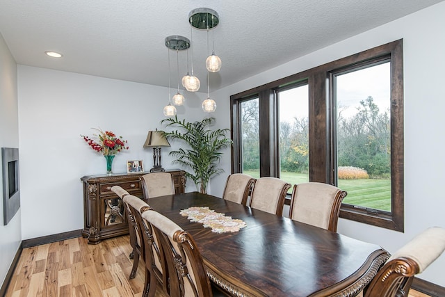 dining space featuring a textured ceiling and light wood-type flooring