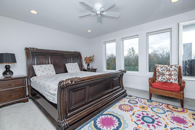 bedroom with ceiling fan, light colored carpet, and a textured ceiling