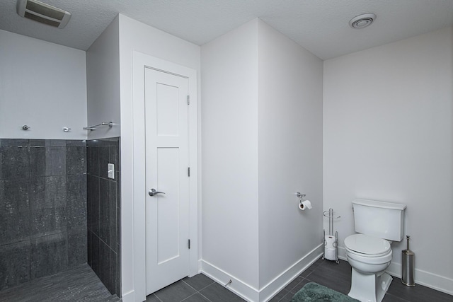 bathroom with toilet, tile patterned flooring, and a textured ceiling