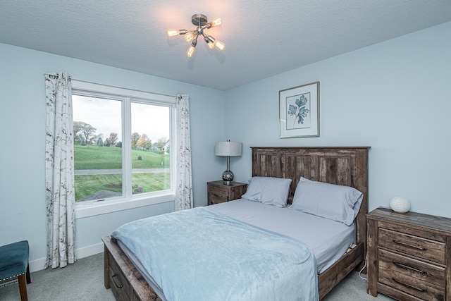 bedroom featuring an inviting chandelier, light carpet, and a textured ceiling