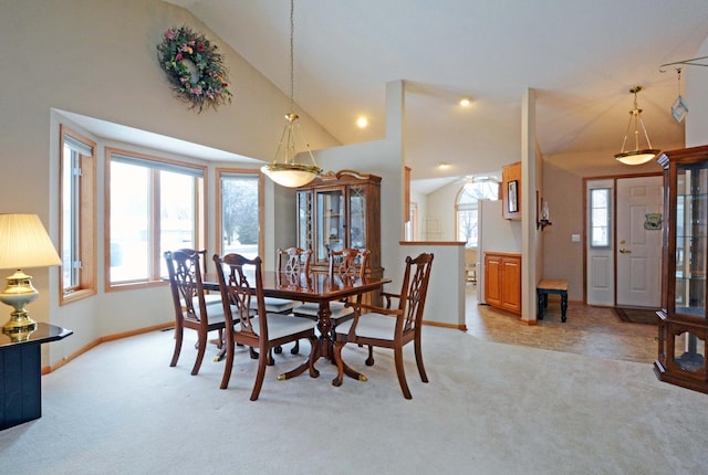 carpeted dining area with high vaulted ceiling