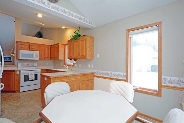 kitchen featuring white appliances, lofted ceiling, kitchen peninsula, and sink