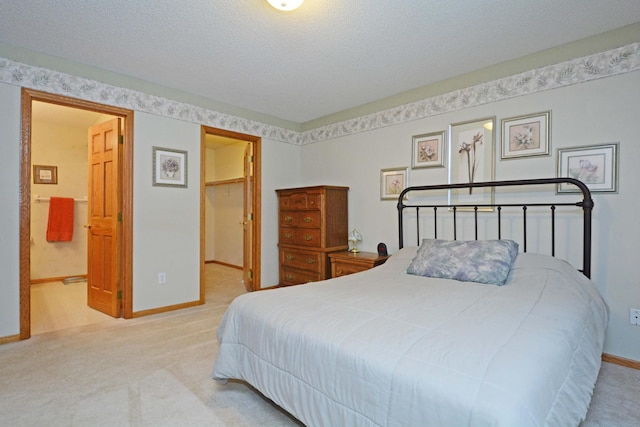 bedroom featuring light colored carpet, a spacious closet, and a textured ceiling