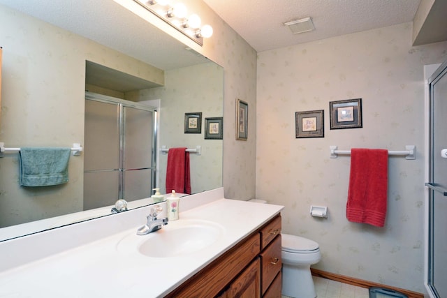 bathroom featuring vanity, a shower with door, toilet, and a textured ceiling