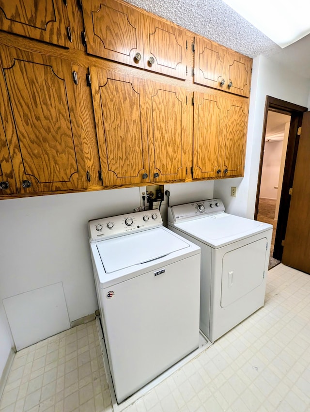 clothes washing area with light floors, separate washer and dryer, and cabinet space