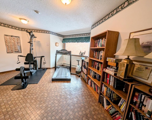 exercise room featuring a textured ceiling and baseboards