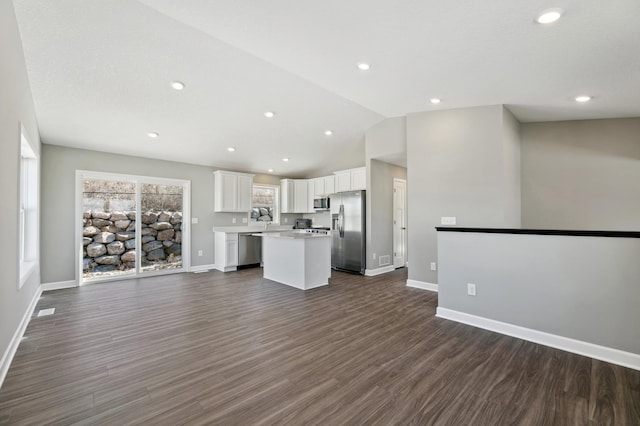 kitchen with stainless steel appliances, a center island, white cabinets, and dark hardwood / wood-style flooring