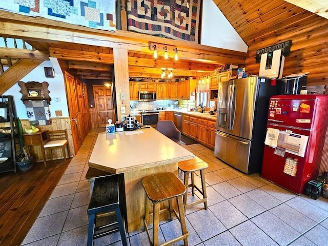 kitchen featuring lofted ceiling, backsplash, stainless steel appliances, a kitchen breakfast bar, and log walls