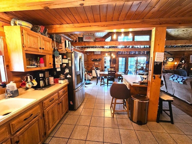 kitchen with beamed ceiling, a breakfast bar area, stainless steel fridge, and wood ceiling