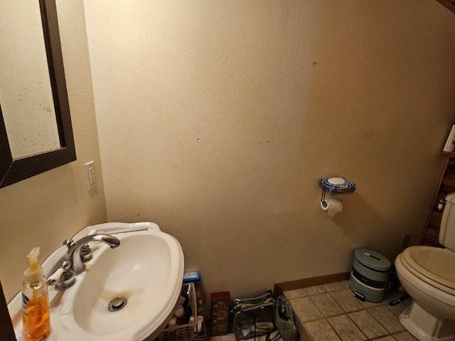 bathroom featuring toilet, tile patterned flooring, and sink