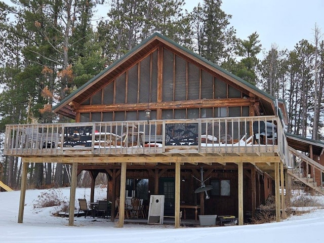 snow covered back of property with a deck