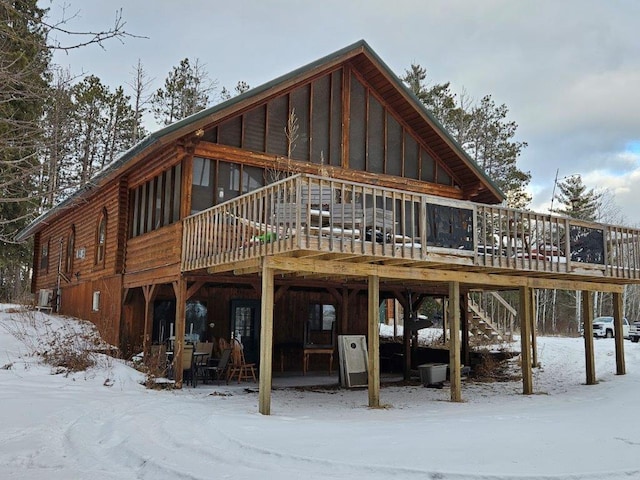 snow covered rear of property featuring a deck