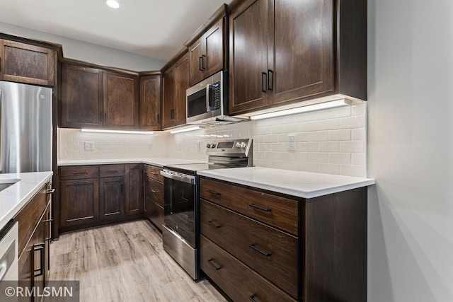 kitchen with appliances with stainless steel finishes, decorative backsplash, dark brown cabinetry, and light hardwood / wood-style floors