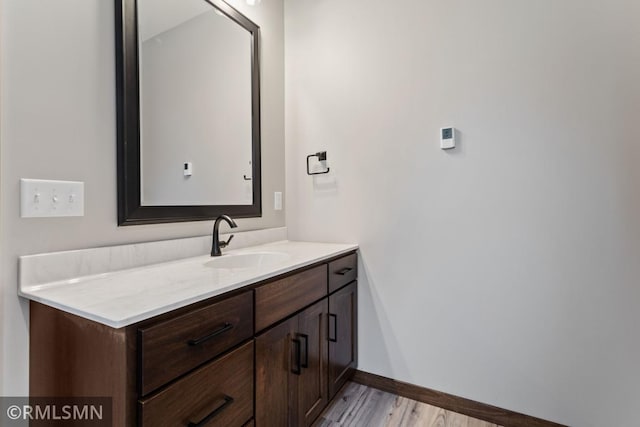 bathroom with baseboards, wood finished floors, and vanity