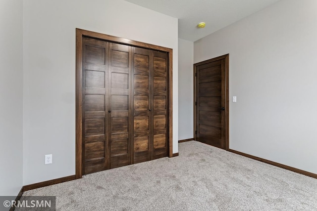 unfurnished bedroom featuring a closet, baseboards, and carpet floors