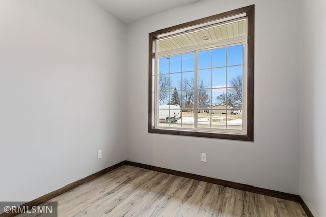 empty room with baseboards and light wood-type flooring