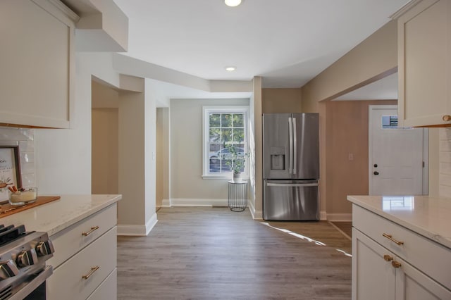 kitchen featuring stainless steel appliances, light stone counters, and light hardwood / wood-style floors