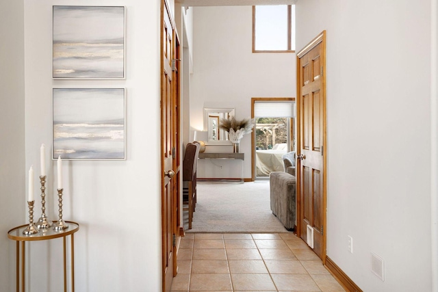 corridor featuring light tile patterned flooring, plenty of natural light, light carpet, and visible vents