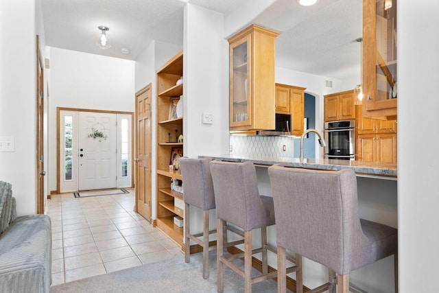 kitchen featuring open shelves, light tile patterned flooring, backsplash, and a sink