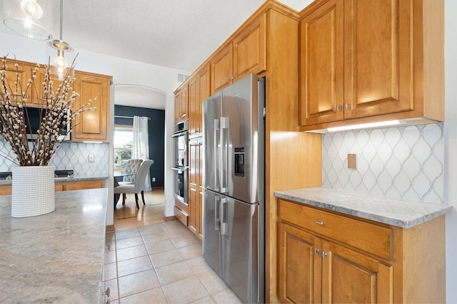 kitchen featuring light tile patterned floors, stainless steel appliances, visible vents, and brown cabinetry