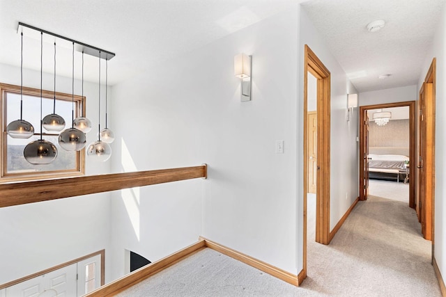 corridor featuring a textured ceiling, baseboards, and carpet