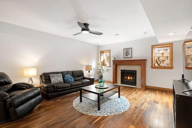 living area with a ceiling fan, hardwood / wood-style flooring, a fireplace, and baseboards